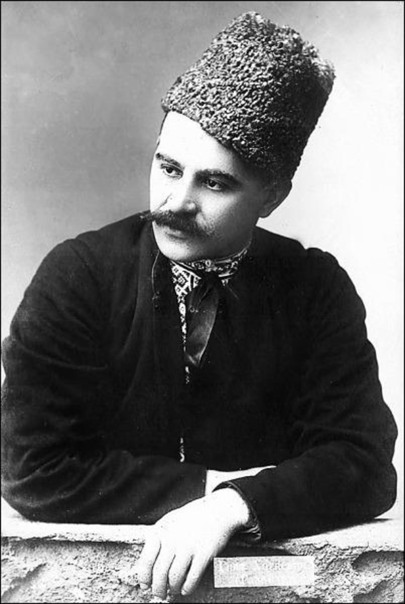 Kobzar Gnat Hotkevich with mustache in national cap and shirt with Ukrainian national ornament looking out from under a zhupan. Black and white photo. Sitting leaning on the table. Authentic old photo.