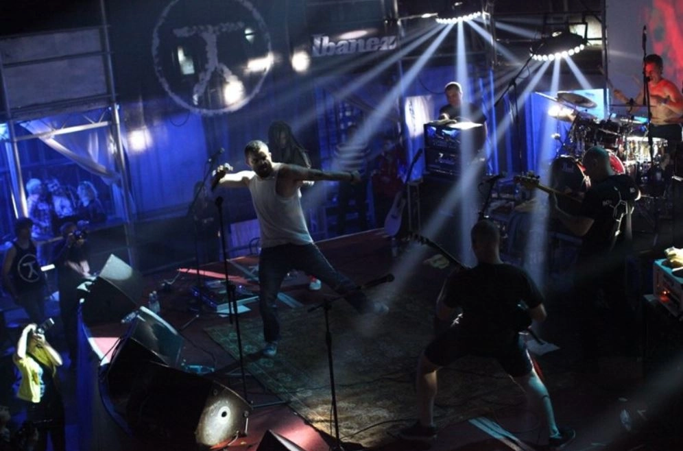 A dynamic metal group is unleashing their sound on stage, surrounded by a kaleidoscope of radiant lights that cut through the darkness. This vivid portrayal conveys the raw power and captivating essence of a live performance, resembling a stunning frame from an unforgettable concert experience.