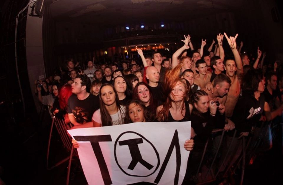 Fans of the band Tol gathered in clusters, their excitement palpable as they held up a poster adorned with the band's logo. Among them, girls dressed in colorful band tees and t-shirts swayed to the music, their faces lit up with joy. Many wear glittery accessories—headbands, bracelets.