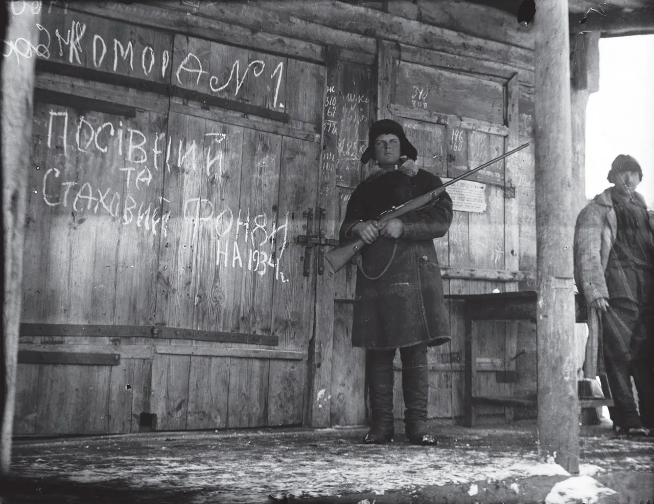 An armed Komsomol member guards a granary with grain, Vilshany village, now Dergachiv district, Kharkiv region